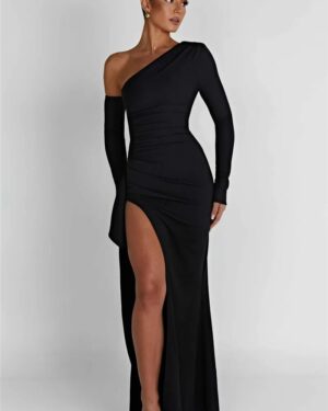 Woman wearing a black one-shoulder maxi dress with long sleeves, ruched detailing, a cascading side drape, and high thigh slit.