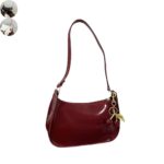 Burgundy red patent shoulder bag with glossy finish, long strap, gold hardware and decorative red cherry charm