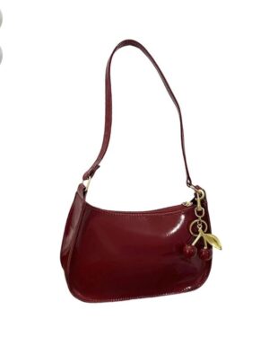 Burgundy red patent shoulder bag with glossy finish, long strap, gold hardware and decorative red cherry charm