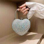 Cupid Rhinestone Heart Clutch (13) Silver AB rhinestone heart clutch bag held by hand with iridescent crystals and silver metal top handle
