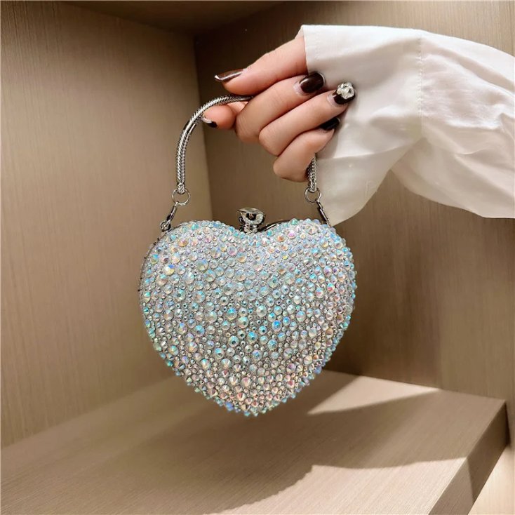 Silver AB rhinestone heart clutch bag held by hand with iridescent crystals and silver metal top handle