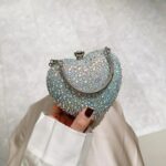Cupid Rhinestone Heart Clutch (3) Silver AB rhinestone heart clutch bag held by hand with iridescent crystals, silver frame and metal handle