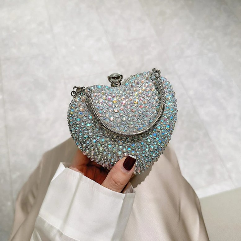 Silver AB rhinestone heart clutch bag held by hand with iridescent crystals, silver frame and metal handle