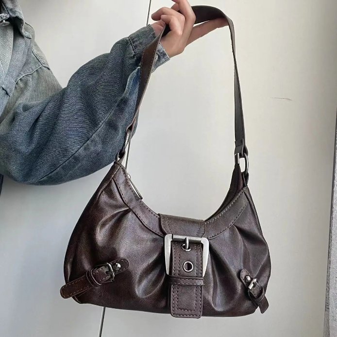 Brown Dalton Retro Buckle Shoulder Bag held by its long strap, showing a soft curved silhouette and silver-tone buckle details