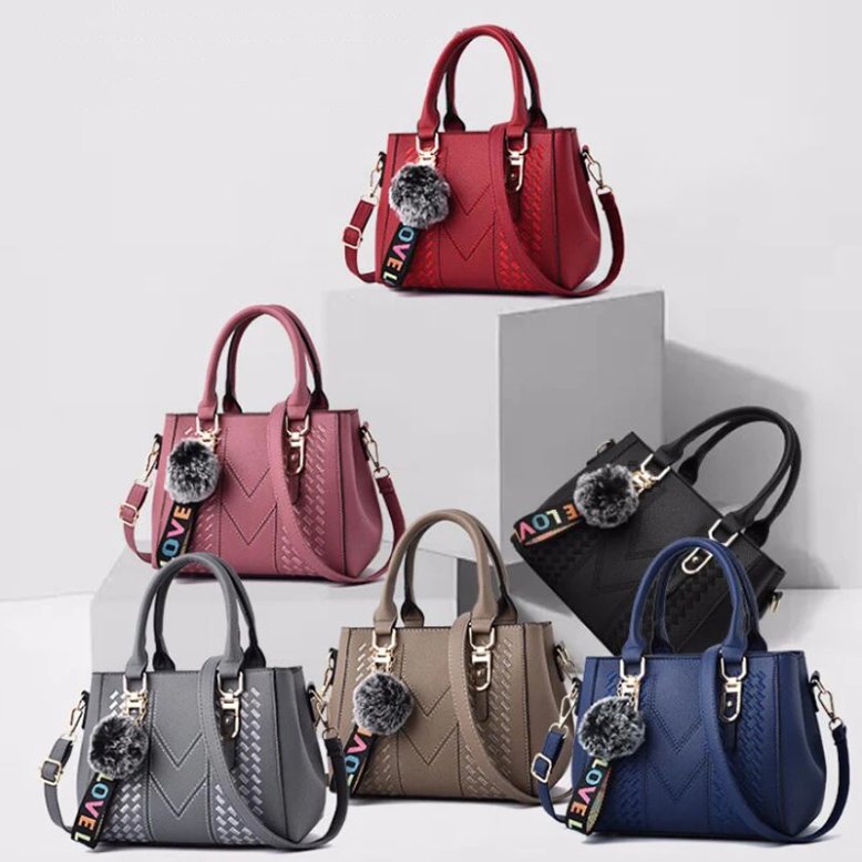Darling Pom Pom handbags displayed in red, pink, black, gray, taupe and blue with top handles and shoulder straps
