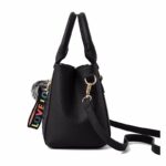 Side view of black Darling Pom Pom handbag showing structured shape, double handles and detachable shoulder strap