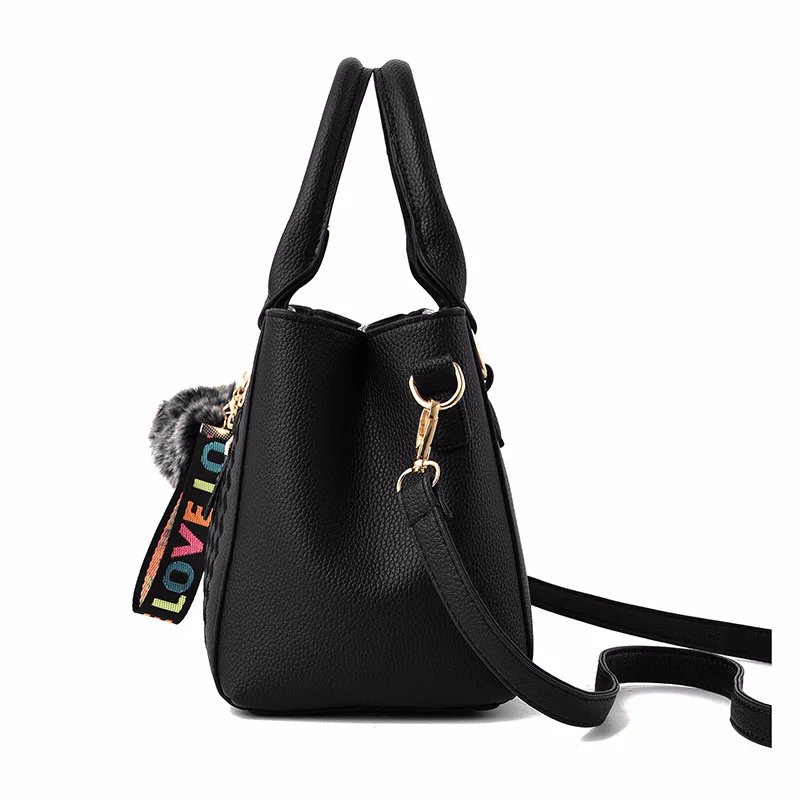 Side view of black Darling Pom Pom handbag showing structured shape, double handles and detachable shoulder strap