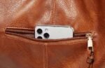 Delaney Large Hobo Bag-brown (10) Close-up of brown Delaney Large Hobo Bag exterior zipper pocket holding a smartphone, highlighting convenient storage and gold-tone zipper hardware