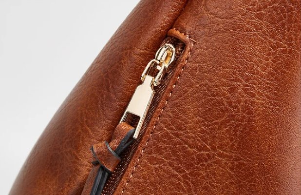 Detailed close-up of brown Delaney Large Hobo Bag showing gold-tone zipper pull, decorative leather-look tassel and textured stitching