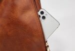 Delaney Large Hobo Bag-brown (9) Close-up of brown Delaney Large Hobo Bag showing a smartphone partially inserted into the side zipper pocket and detailed textured material