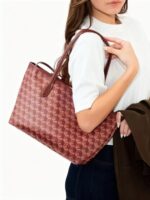Woman wearing burgundy Ellery Geometric Print Tote Bag over her shoulder with a white top and dark jeans, showcasing its large geometric patterned design