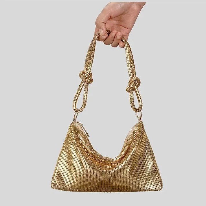 Gold metallic mesh evening bag held by its knotted shoulder strap with shimmering finish and relaxed slouchy shape