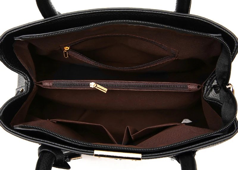 Open black top handle satchel bag showing lined interior with zippered divider and multiple storage pockets