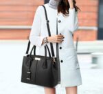 Woman carrying black structured top handle satchel bag with long detachable shoulder strap