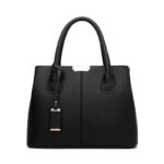 Front view of black textured top handle satchel bag with structured silhouette and decorative hanging detail