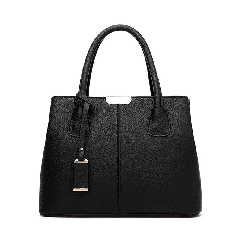 Front view of black textured top handle satchel bag with structured silhouette and decorative hanging detail