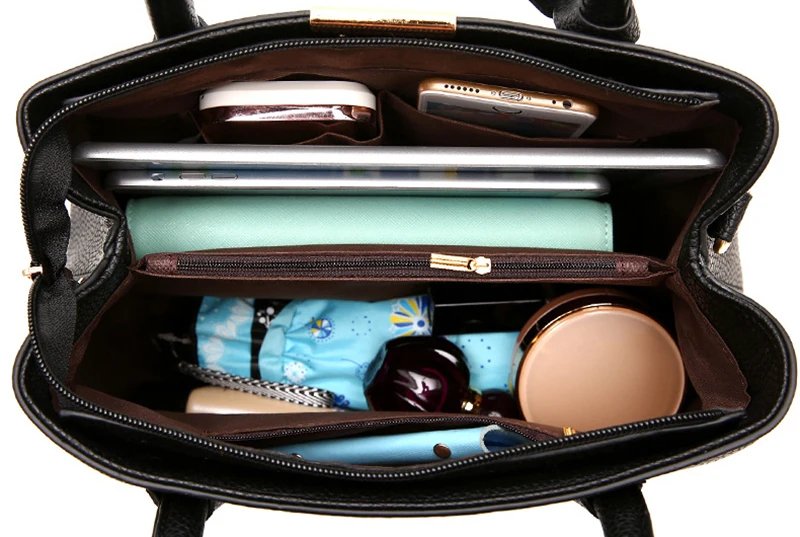 Open black satchel handbag showing spacious organised interior with multiple compartments for everyday essentials