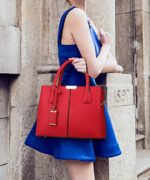 Woman carrying wine red Harper top handle satchel bag with structured design and double handles