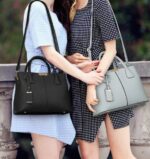 Women carrying black and light gray Harper top handle satchel bags with structured designs and shoulder straps