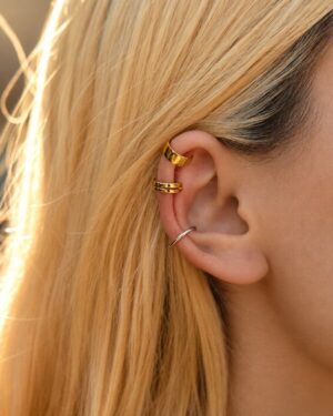 Close-up of a woman wearing gold and silver Lucienne clip-on ear cuff earrings styled along the upper and middle ear.