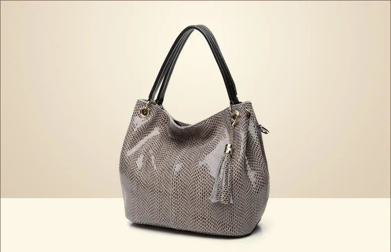 Beige snake embossed hobo handbag for women with double black handles, slouchy shape, tassel charm, and gold tone hardware