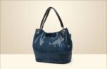 Mamba Snake Embossed Hobo Bag (6) Blue snake embossed women’s hobo bag with double black shoulder handles, textured finish, tassel charm, and gold tone hardware