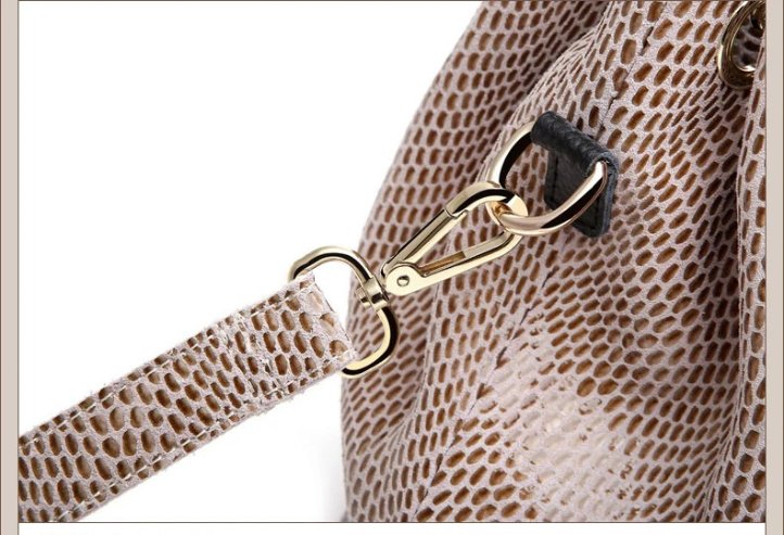 Close-up of beige snake embossed hobo bag adjustable shoulder strap attached with a gold tone swivel clasp and metal ring