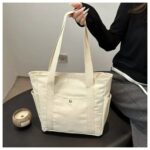 Maren Canvas Tote Bag-beige (5) Woman holding beige Maren Canvas Tote Bag with long shoulder handles, roomy rectangular shape and practical exterior pockets