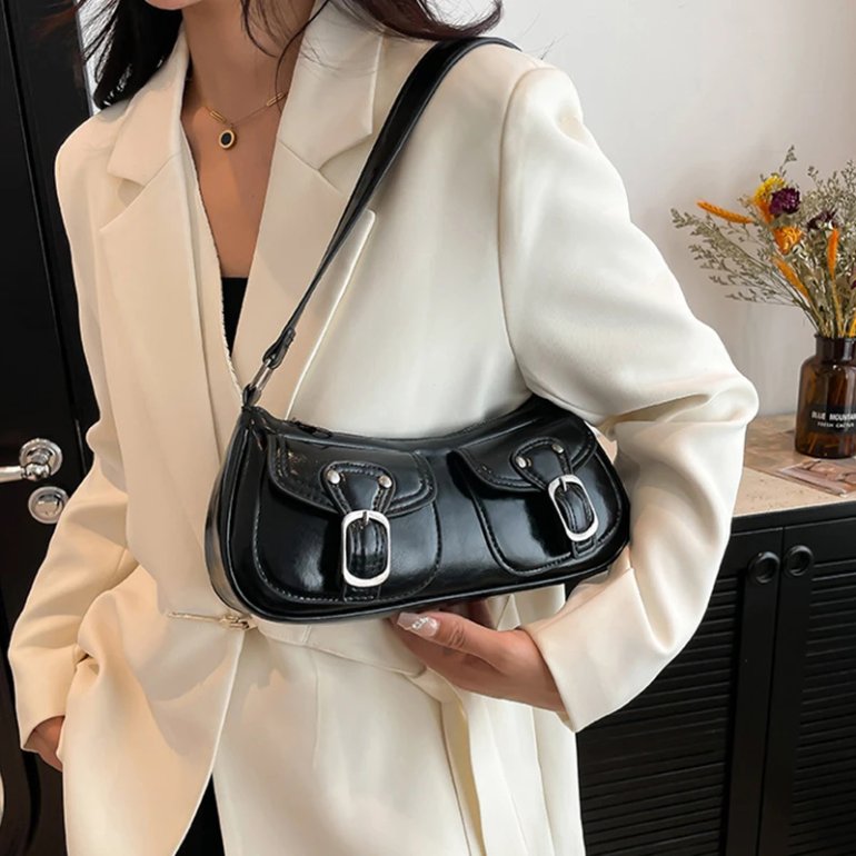 Black Quinn Double Pocket Shoulder Bag worn over the shoulder with two front buckle pockets, glossy finish and silver hardware
