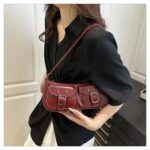 Quinn Double Pocket Shoulder Bag-burgundy (2) Burgundy Quinn Double Pocket Shoulder Bag worn over the shoulder with twin front buckle pockets, curved shape and glossy finish