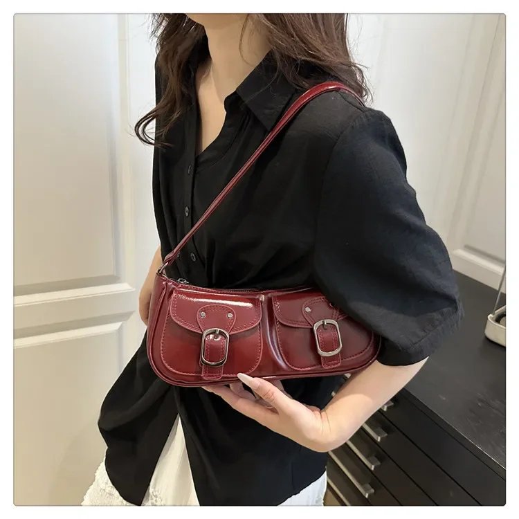 Burgundy Quinn Double Pocket Shoulder Bag worn over the shoulder with twin front buckle pockets, curved shape and glossy finish