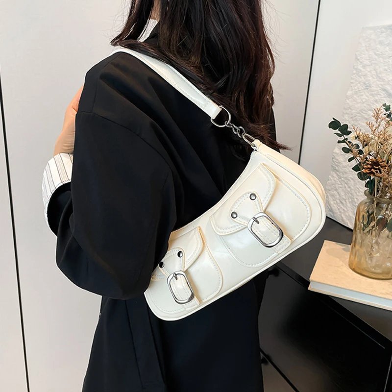White Quinn Double Pocket Shoulder Bag worn over the shoulder with twin front buckle pockets, silver hardware and curved silhouette