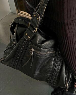 Black Reese Vintage Washed Shoulder Bag with distressed leather-look texture, braided detailing, gold-tone hardware and front zipper pocket worn over the shoulder