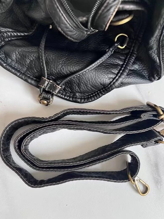 Detachable adjustable shoulder strap of black Reese Vintage Washed Shoulder Bag with matching textured finish and antique gold-tone swivel clasps