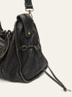 Reese Vintage Washed Shoulder Bag (3) Close-up side view of black Reese Vintage Washed Shoulder Bag showing textured leather-look material, zipper closure, gold-tone rings and decorative side ties