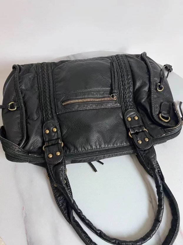 Top view of black Reese Vintage Washed Shoulder Bag showing braided front panels, zipper pocket, double handles and decorative gold-tone rivets