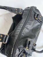 Reese Vintage Washed Shoulder Bag (9) Close-up of Reese Vintage Washed Shoulder Bag showing full-length top zipper closure, textured black exterior and gold-tone strap attachment rings