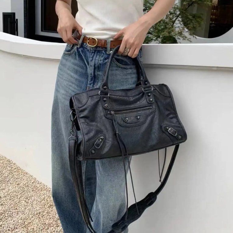 Black Ridley Rivet Motorcycle Bag styled with casual jeans, featuring double top handles, front zip pocket, buckle details and long strap