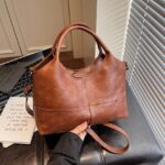 Rowan Retro Crossbody Bag-brown (3) Brown Rowan retro crossbody bag shown by hand with rounded handles and detachable shoulder strap