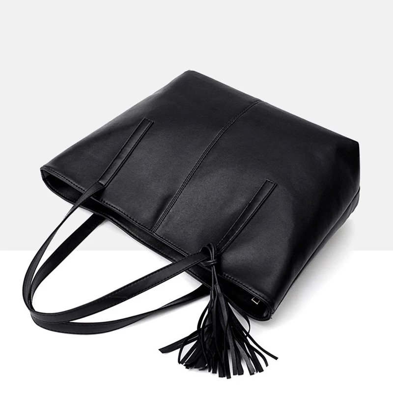 Angled top view of Sable black tassel tote bag showing long handles, structured body and decorative tassel