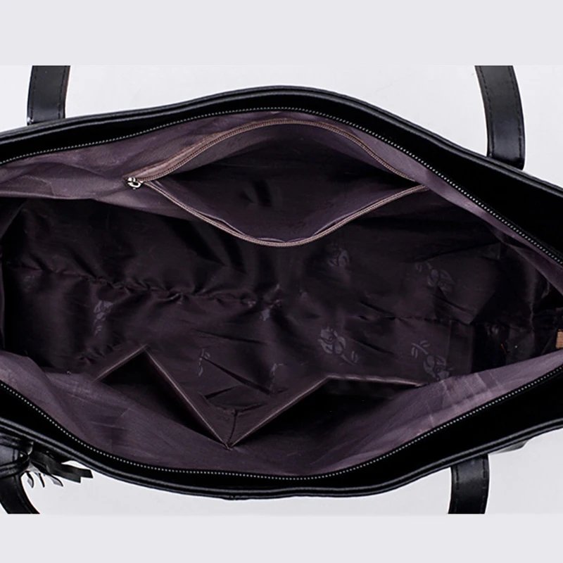 Interior view of Sable black tassel tote bag showing spacious lined compartment with internal zip and slip pockets