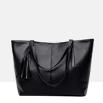 Sable black tassel tote bag with long handles draped across the front and decorative tassel detail