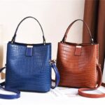 Sienna Croc Pattern Bucket Bag (2) Sienna croc pattern bucket bags in blue and light brown with top handles, long shoulder straps and gold tone hardware