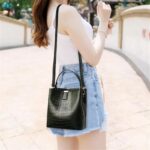 Sienna Croc Pattern Bucket Bag-black (6) Woman wearing black Sienna croc pattern bucket bag as a crossbody handbag with adjustable shoulder strap