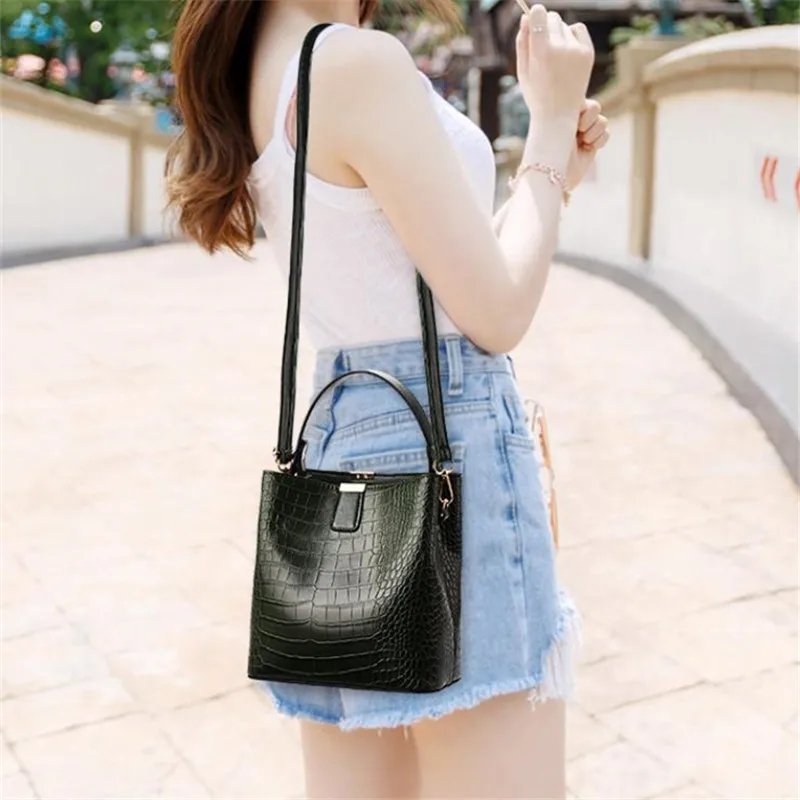 Woman wearing black Sienna croc pattern bucket bag as a crossbody handbag with adjustable shoulder strap
