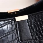 Sienna Croc Pattern Bucket Bag-black (7) Close-up of black Sienna croc pattern bucket bag showing textured finish, tab closure and gold tone hardware