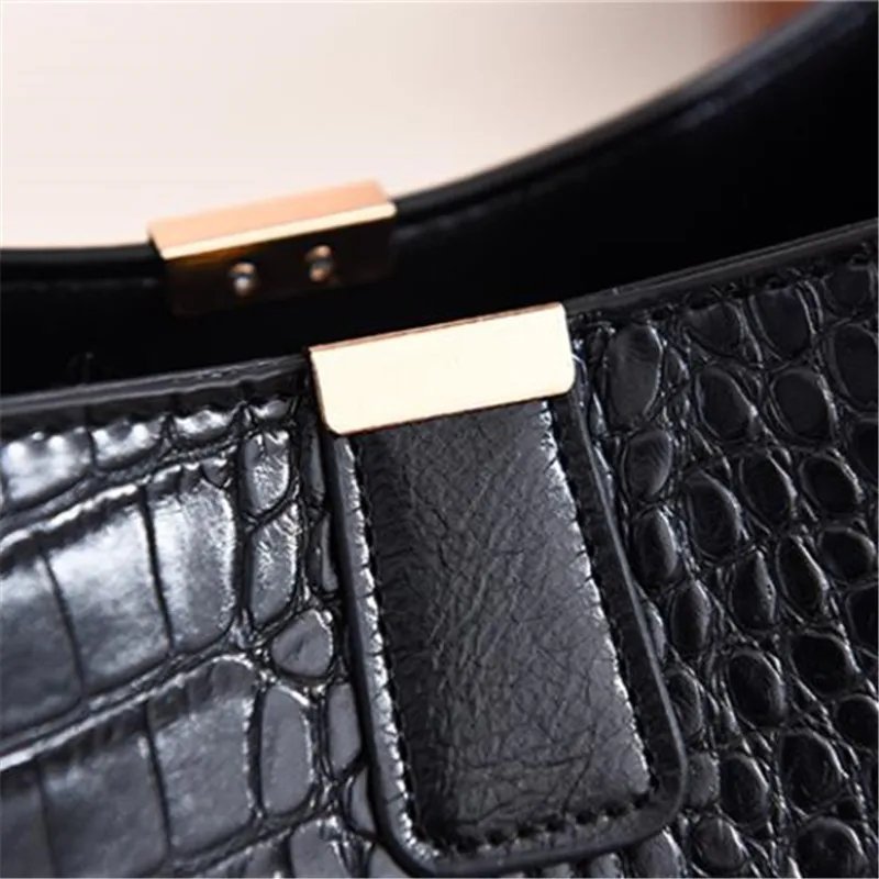 Close-up of black Sienna croc pattern bucket bag showing textured finish, tab closure and gold tone hardware
