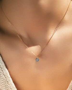 Soline evil eye CZ pendant necklace in gold tone with blue and clear cubic zirconia stones worn by a woman