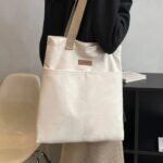 Tegan Large Canvas Tote Bag-white (3) Woman carrying white Tegan Large Canvas Tote Bag over her shoulder with beige woven straps and two large front pockets