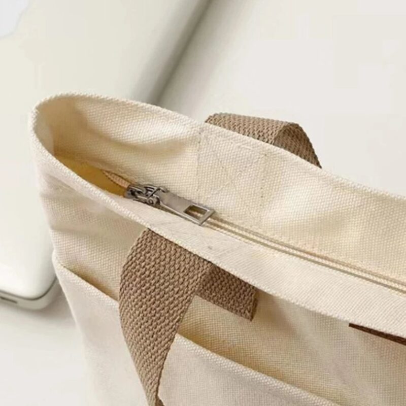 Close-up of white Tegan Large Canvas Tote Bag featuring top zipper closure, silver zipper pull and reinforced beige canvas straps